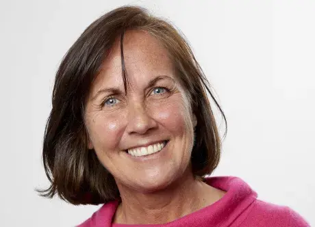 Jac Crang, smiling at the camera in a bright pink turtleneck top