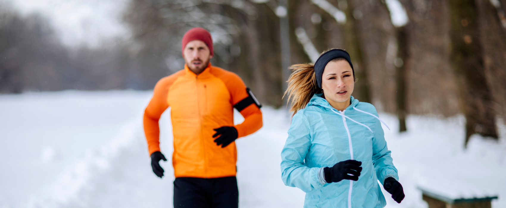 Man and woman running on a snowy road