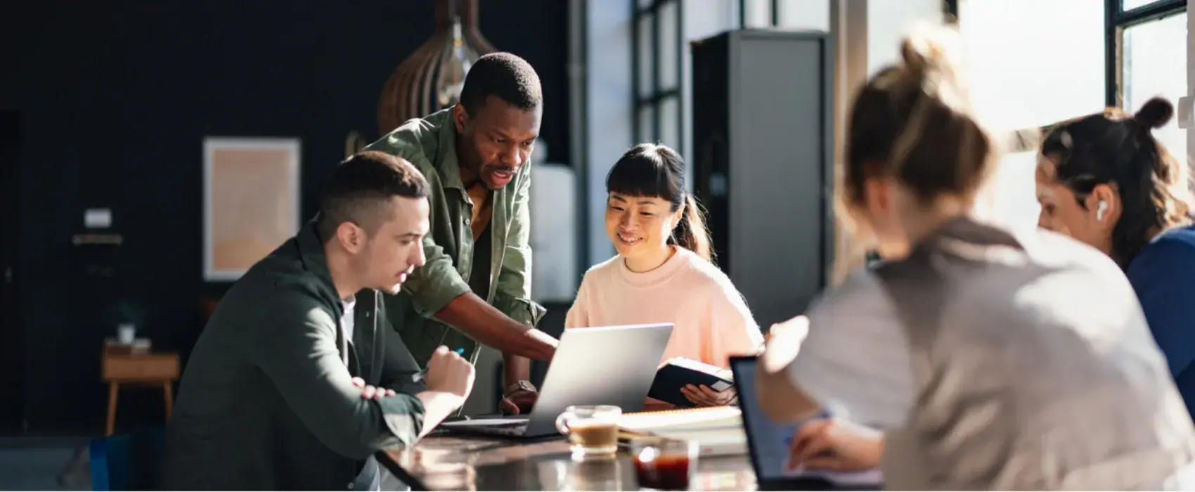 Group of people looking at a laptop around a table