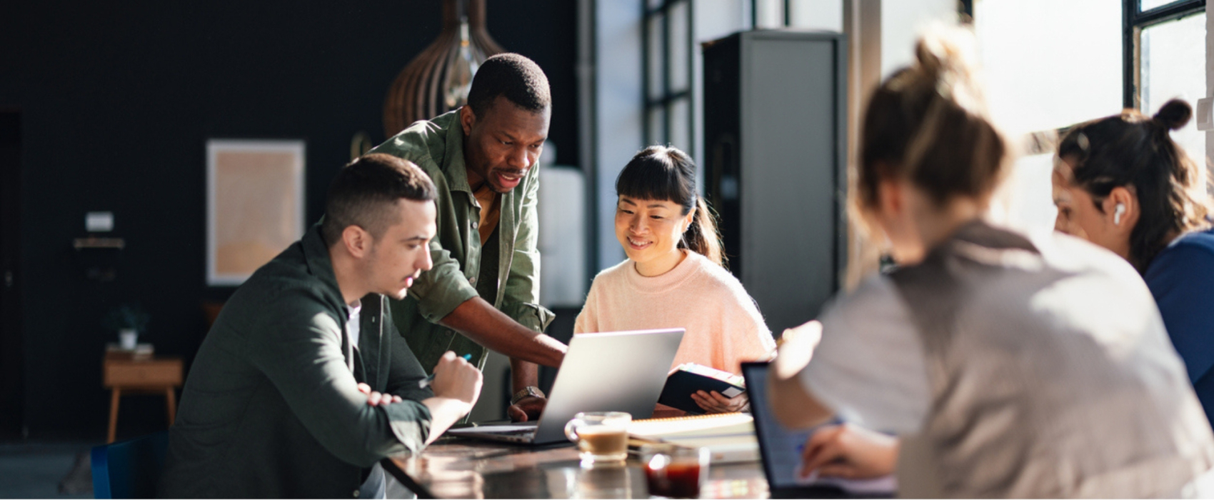 Group of people looking at a laptop around a table