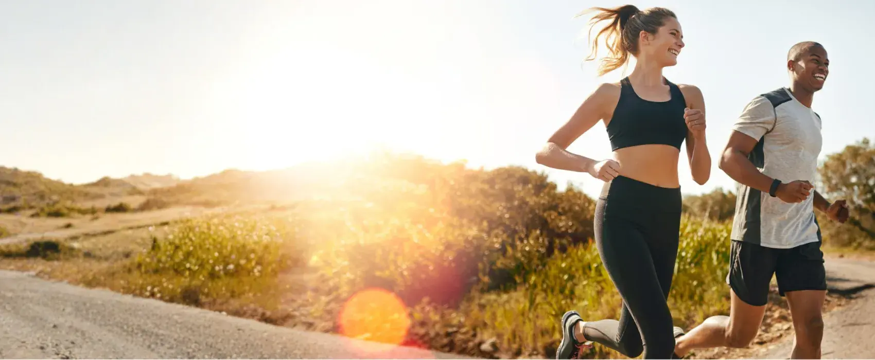 A man and a woman running in the countryside at sunset