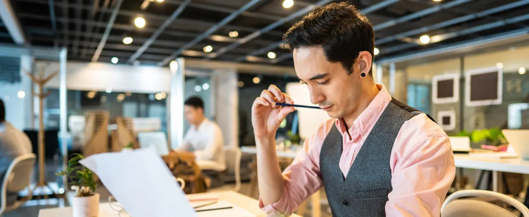 Young man working at a desk with a hearing aid in his ear