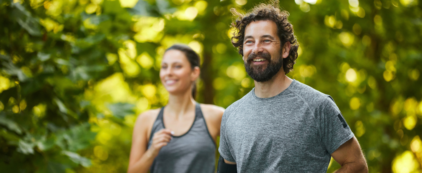 A woman and man running in a forest