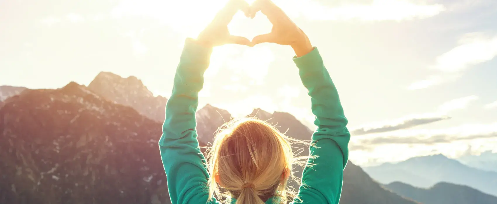 view from a mountain top of a woman making a heart shape with her hands 
