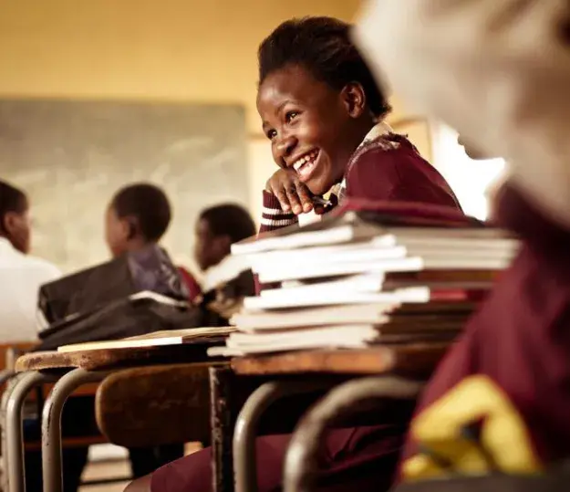 A happy girl sitting at a desk in a classroom, ready to learn