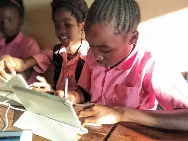 Two girls at school using a tablet to do school work