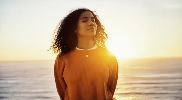 Woman stood infront of a sunrise