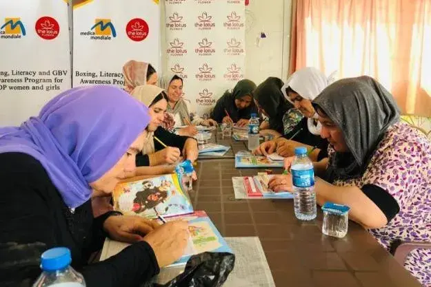 A group of women sitting as a table, surrounded books, engaged in a discussion